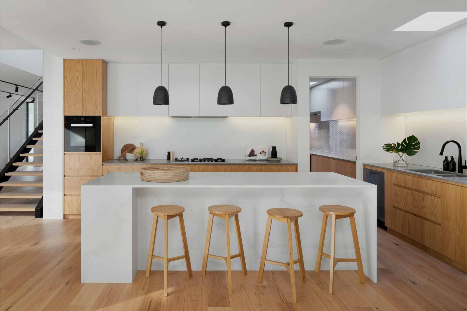 Reforma de cocina con tonos de madera e isla con barra y taburetes